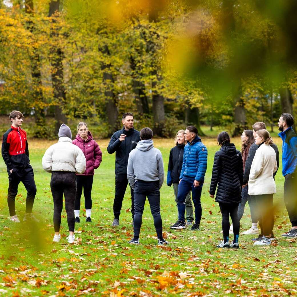 Studenten buiten in een cirkel tijdens sportles