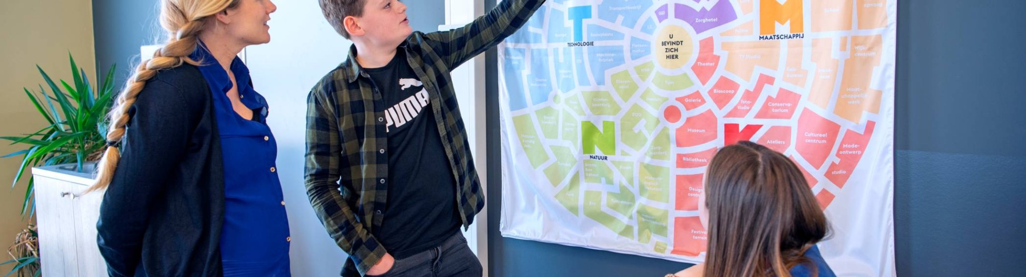 Jongen wijst op poster met docent achter hem voor de fotoshoot van Leerlab bij Citadel 