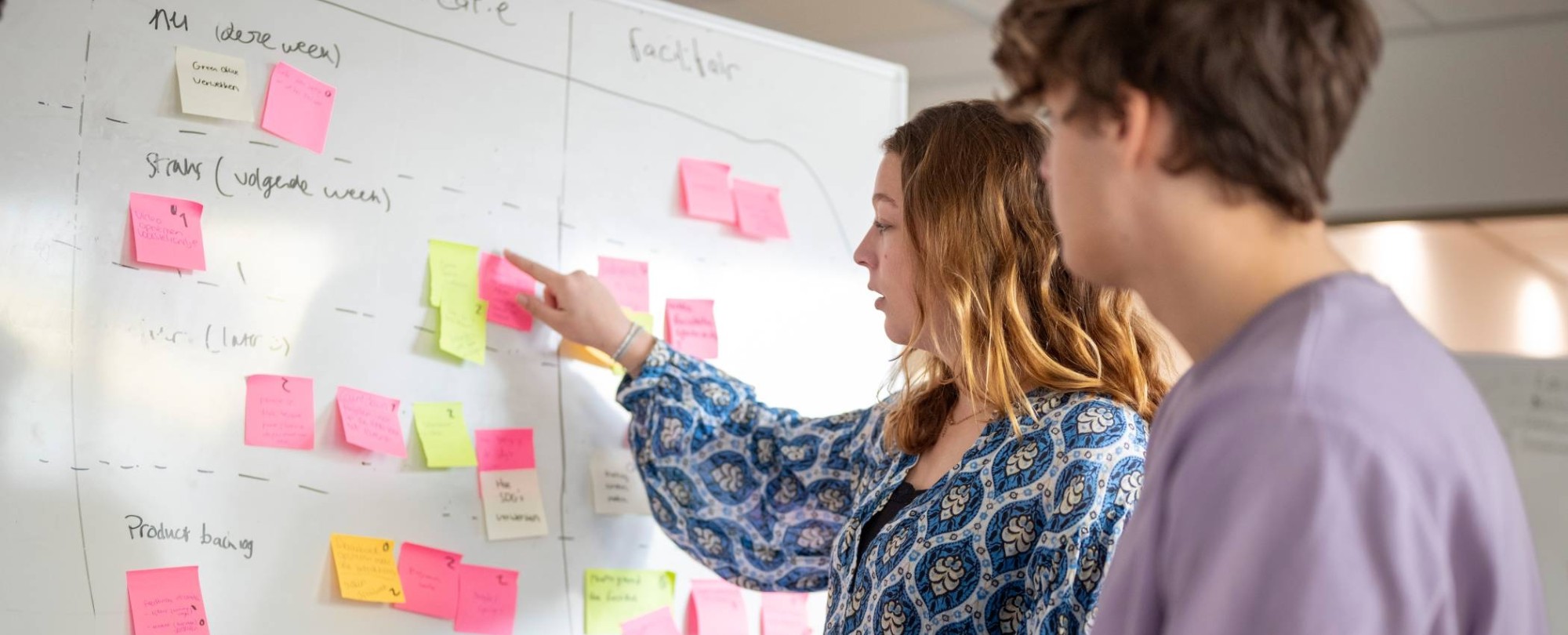 Studenten plakken post-its, projectonderwijs in de klas.