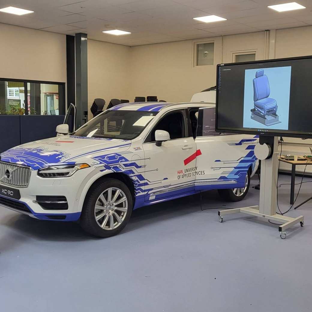 Volvo XC90 die opvallend is gewrapt in een passende lichtblauwe kleurstelling en bijpassend HAN design. 

Deze Volvo XC90 wordt o.a. gebruikt voor het project HUBRIS (HUman-like Behaviour of Robotic In-vehicle Systems). Hierin zal de stoel van de bijrijder aangepast worden om als een rijsimulator de passagier het gevoel te geven dat deze echt meerijdt. Met een VR-bril op zal de testpersoon virtueel de A50 van Arnhem naar Apeldoorn (mee)rijden. Soms bestuurt door een normale 'autopilot', soms door een 'robotbestuurder' die meer mensachtig gedrag vertoont. 

Het doel is uit te vinden of onze mensachtige robot voor de passagier fijner aanvoelt dan de standaardsystemen.
