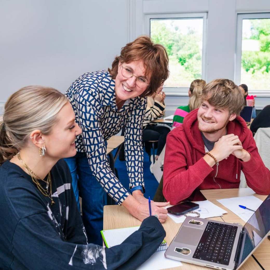 Leraar Fastswitch wijst naar het bord in de klas.