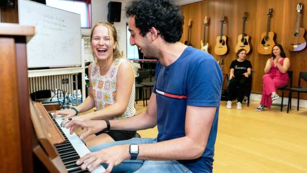 Twee studenten spelen samen op de piano