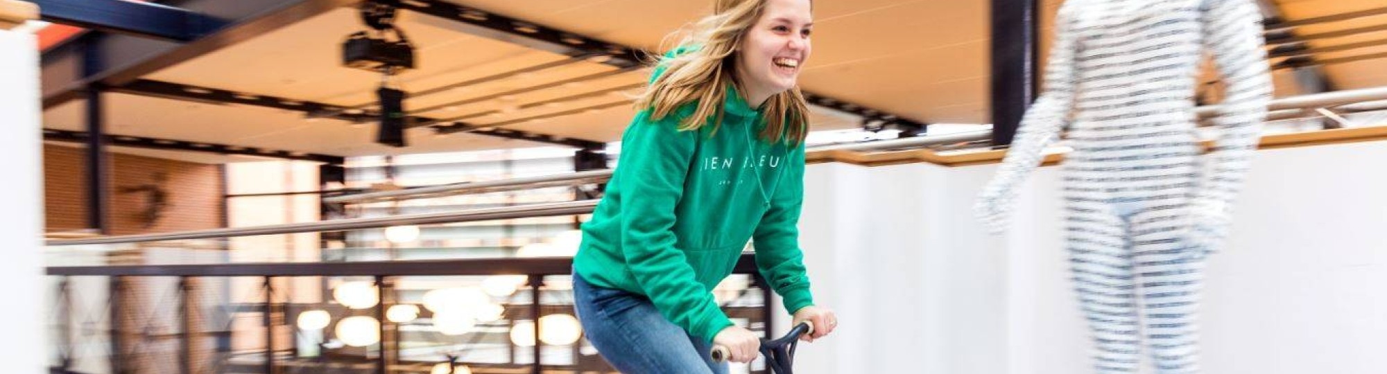 Foto van student Meike Geurtsen die op een step door de gang sjeest.