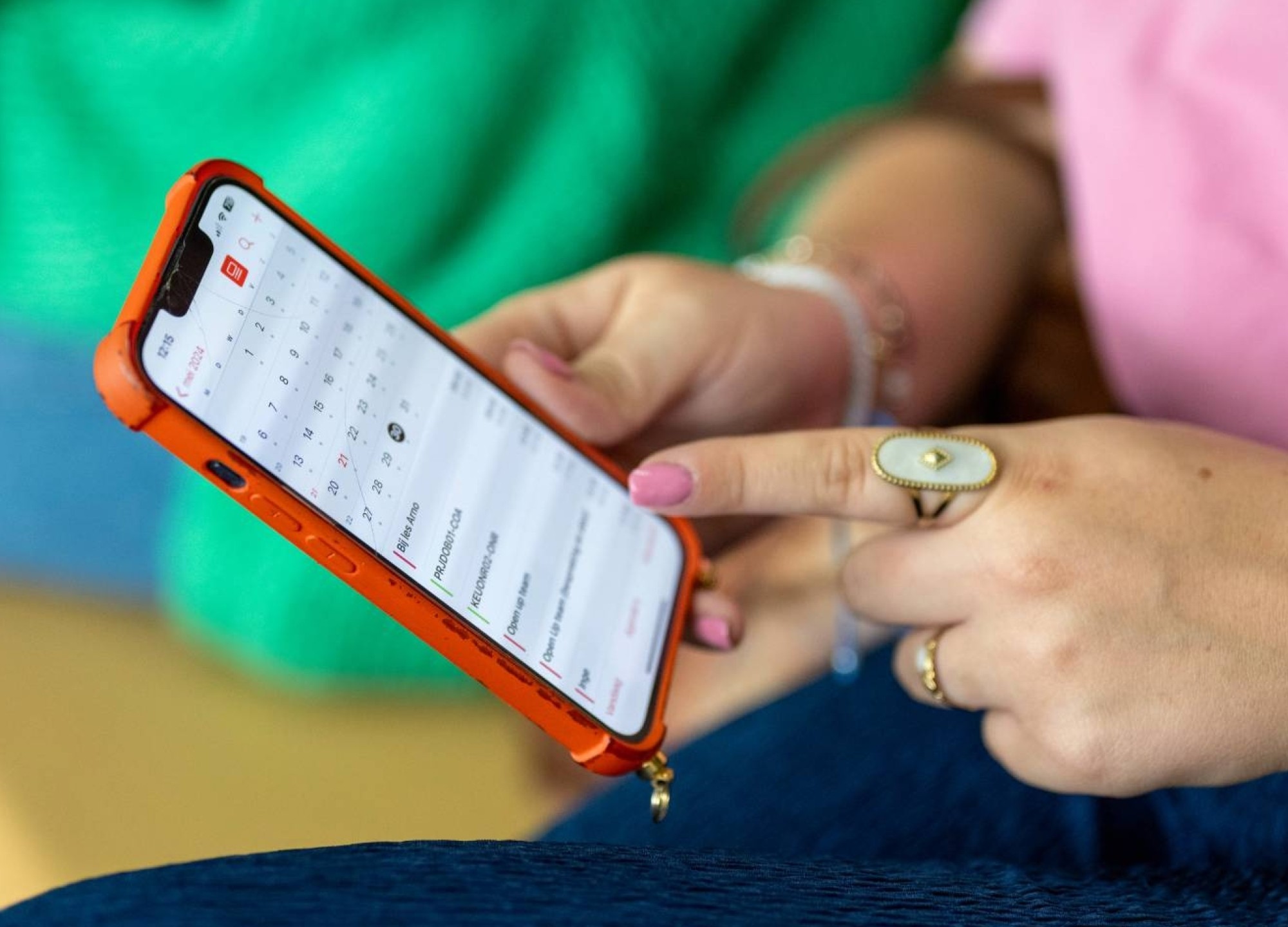 Student houdt haar telefoon vast en wijst er met haar vinger iets op aan. 