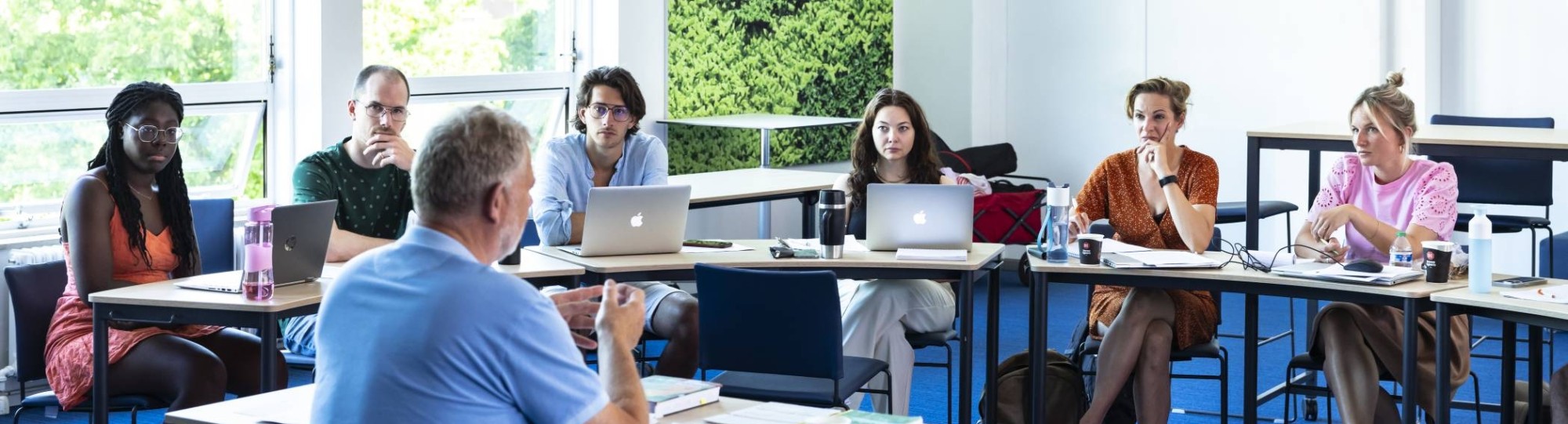 Studenten van de Master Social Work luisteren aandachtig terwijl de docent uitleg geeft.