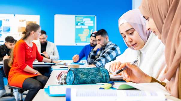 Klas NT2-cursisten aan het werk in een lokaal met blauwe muur.