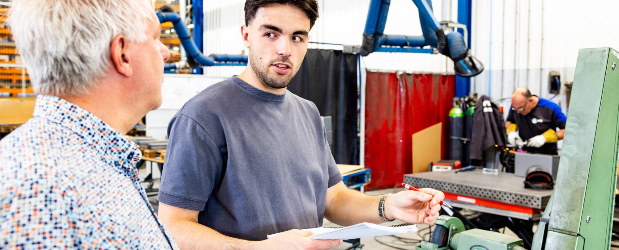 Technische Bedrijfskunde student overlegt met stagebegeleider bij machine.