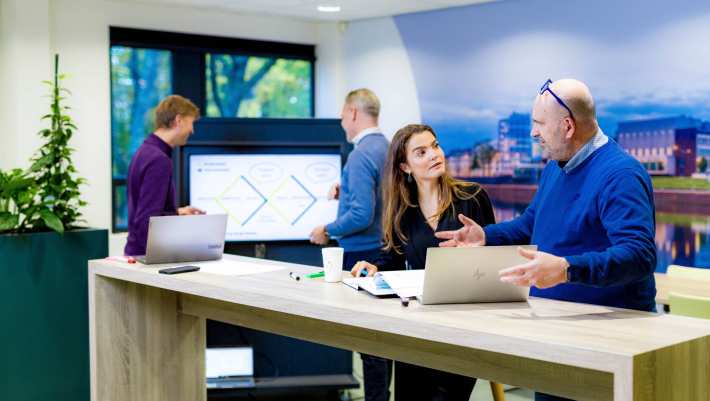 Studenten van de master Business Sales in overleg, samenwerken met laptop.