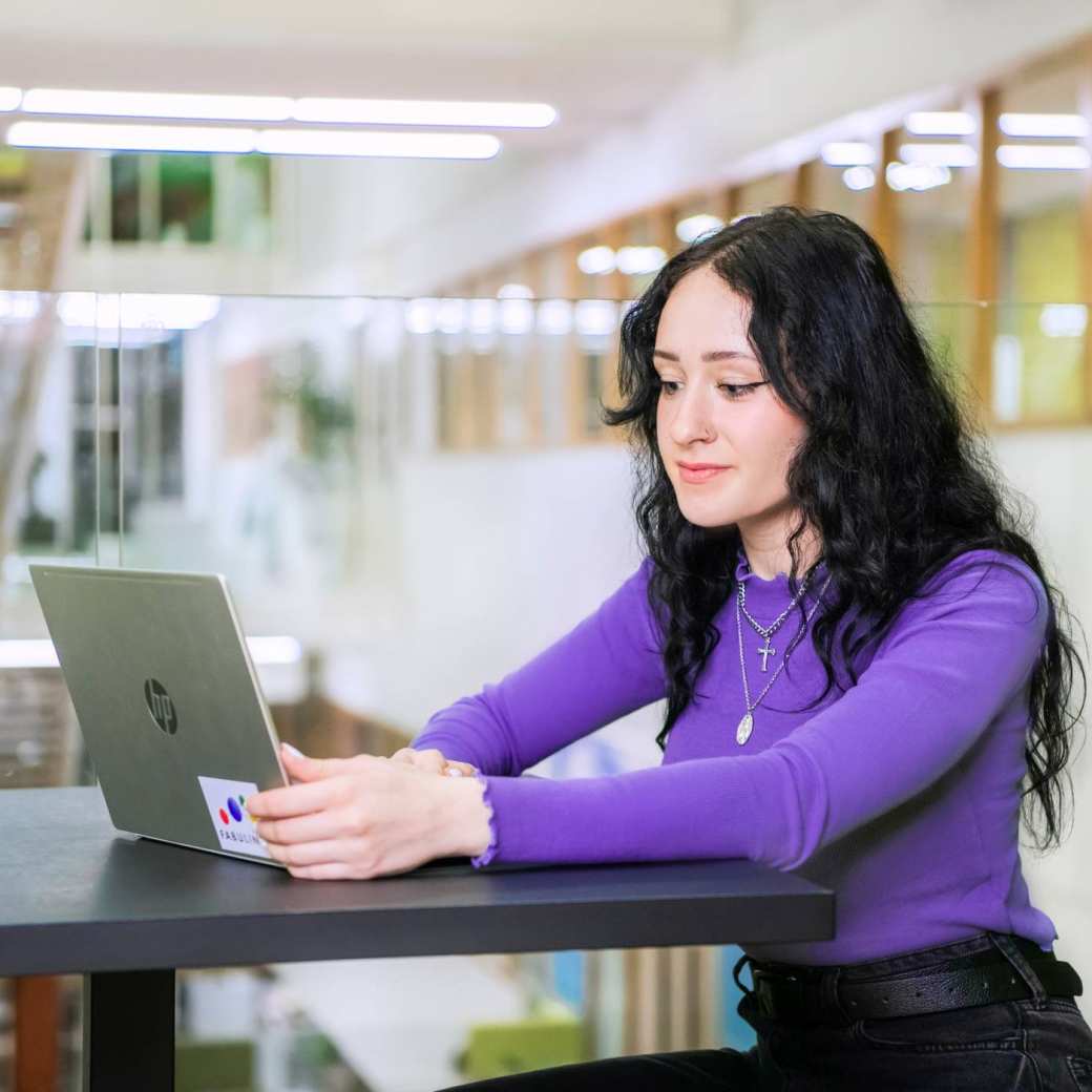 Een student werkt achter haar laptop.
