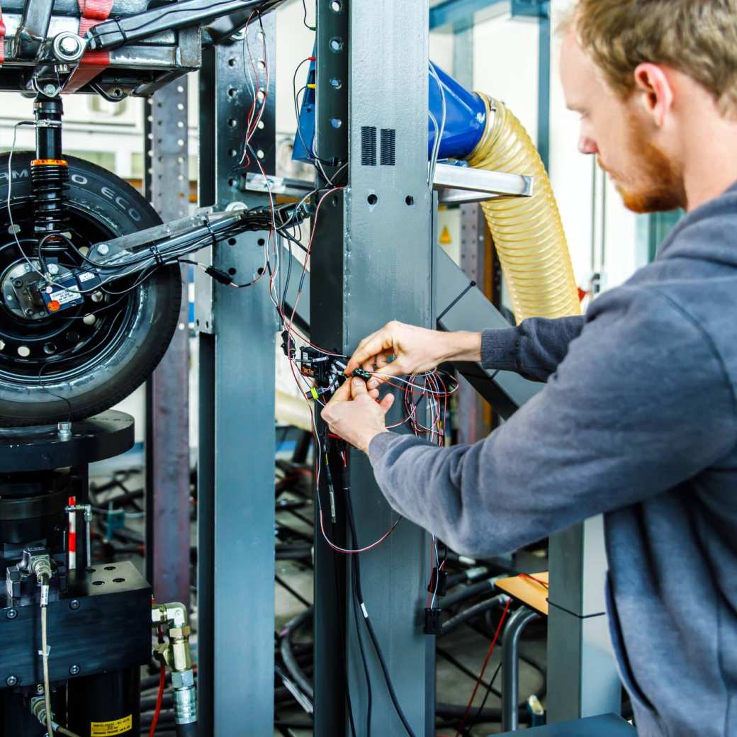 An engineer is connecting wires on a road surface simulator