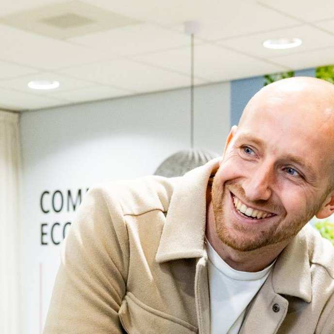 Een student van Logistiek deeltijd in de gang tijdens een pauze, lachend