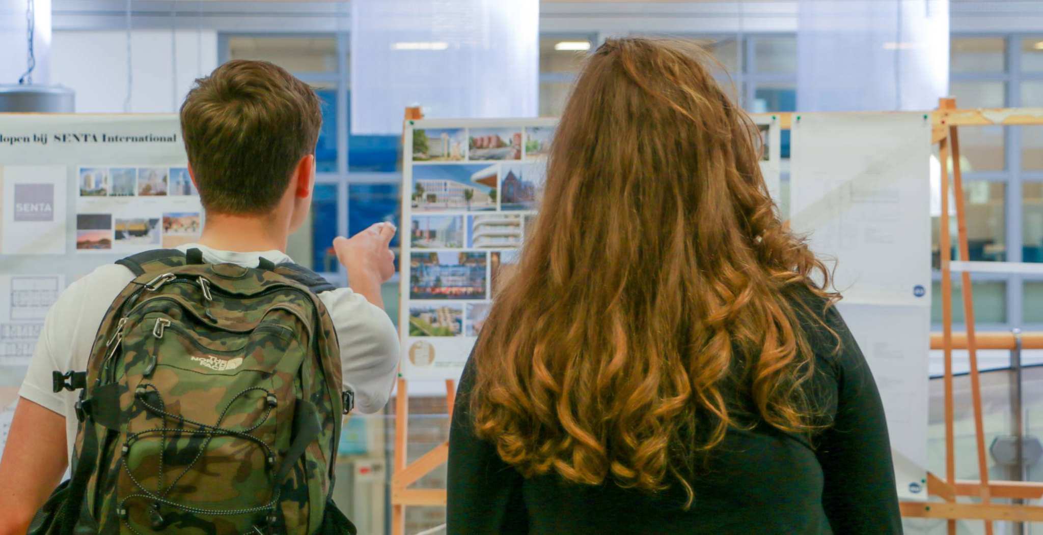 eerstejaarsstudenten bouwkunde bekijken de stagepresentaties van derdejaarsstudenten