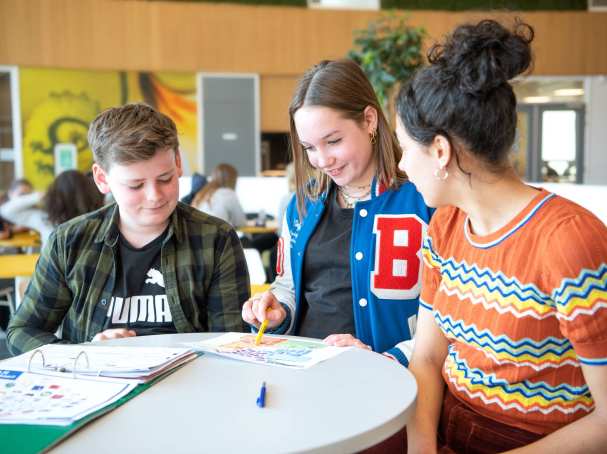 twee studenten in gesprek met docent aan tafel voor de fotoshoot van Leerlab bij Citadel 