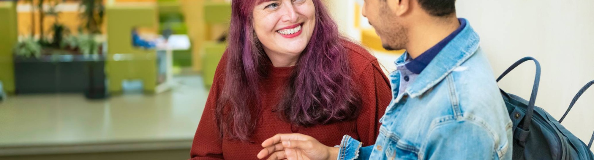 Twee studenten vertellen met elkaar terwijl de een een kladje in de hand heeft met geschreven tekst.