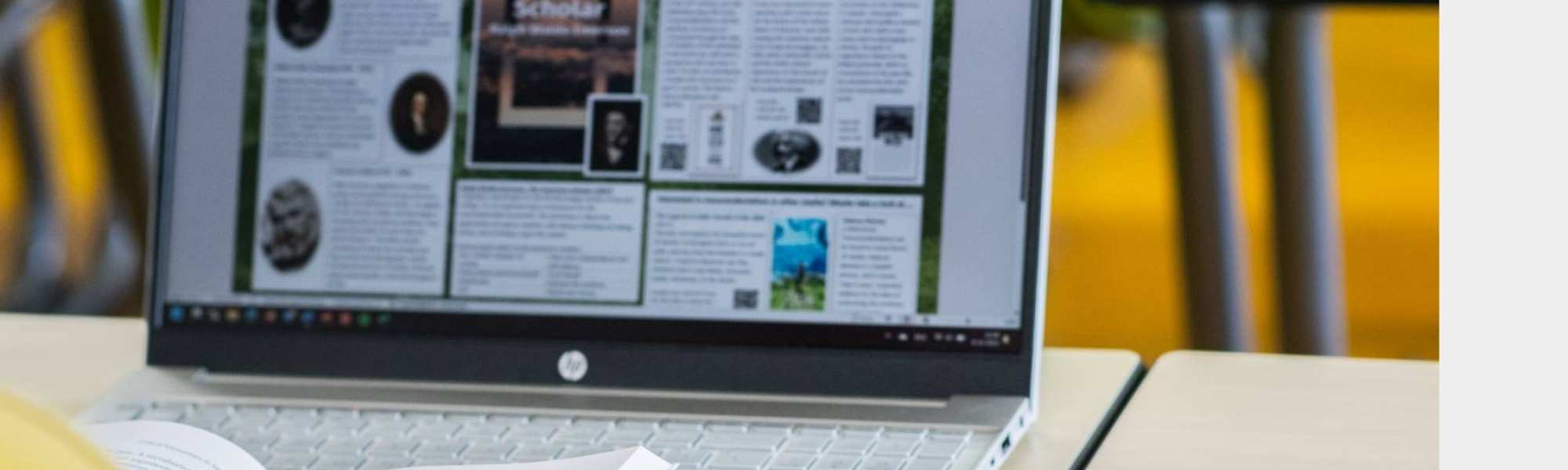Foto Master Academie Educatie. Een masterstudent zit achter haar laptop met een boek opengeslagen in haar handen.