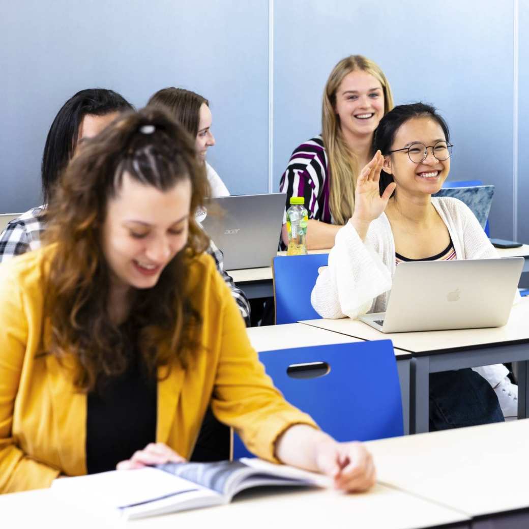 Students in a class, one student puts her hand up