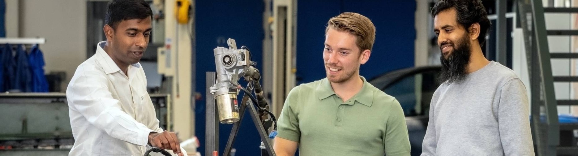 Een docent van de Master Engineering Systems Cyber Physical Systems legt het MORE-project , de scootmobiel, uit aan twee studenten.